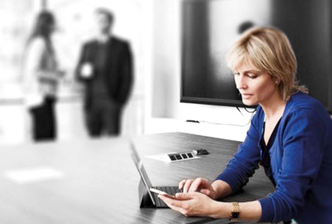 Blonde woman watching her phone in a meeting room